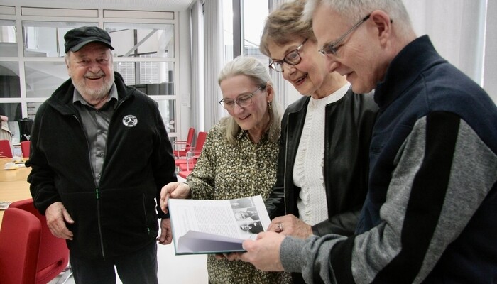 Lahtelainen Alpo Mänttäri (vas.) seuraa vierellä, kun Lahdessa työskentelevä pukkilalainen Kirsi Kujala sekä tapaamisen ensikertalaiset, orimattilalainen Irma Toivari (kesk.) ja lahtelainen Vesa Huusari selailevat Mänttärin Sukuyhdistyksen “Niinipuun varjossa” -historiikkia.