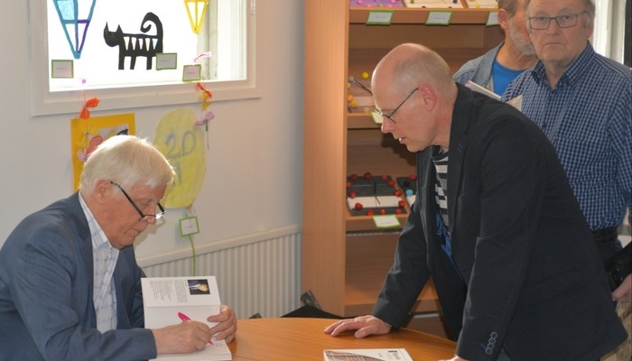 Matti Punttila signeeraa Myllykosken seudun kotiseutuyhdistyksen puheenjohtaja Timo Mynttisen kirjaa. Sippolalainen Matti Paakala odottaa vuoroaan.